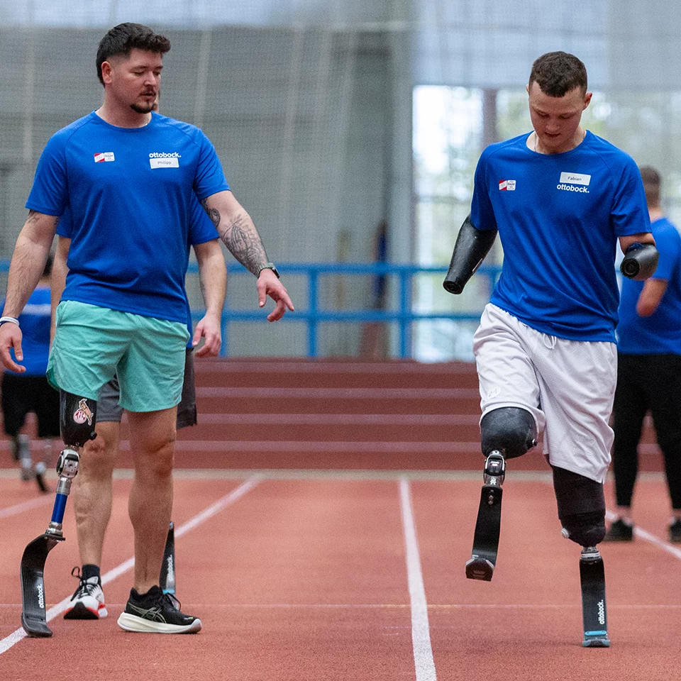 Zwei Sportler und Kunden von APT bereiten sich auf einen Sprint vor, einer hat eine Beinprothese und der zweite trägt zwei Armprothesen und zwei Beinprothesen