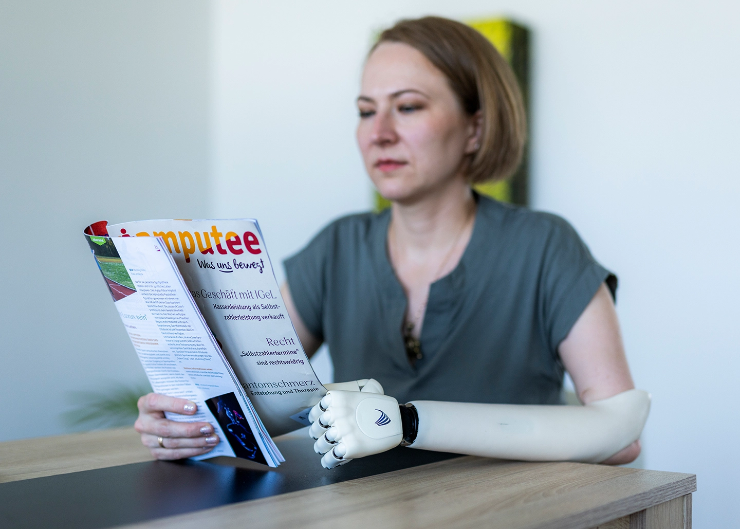 Frau liest ein Magazin über Prothesengemeinschaft, hält die Zeitschrift mit ihrer Armprothese