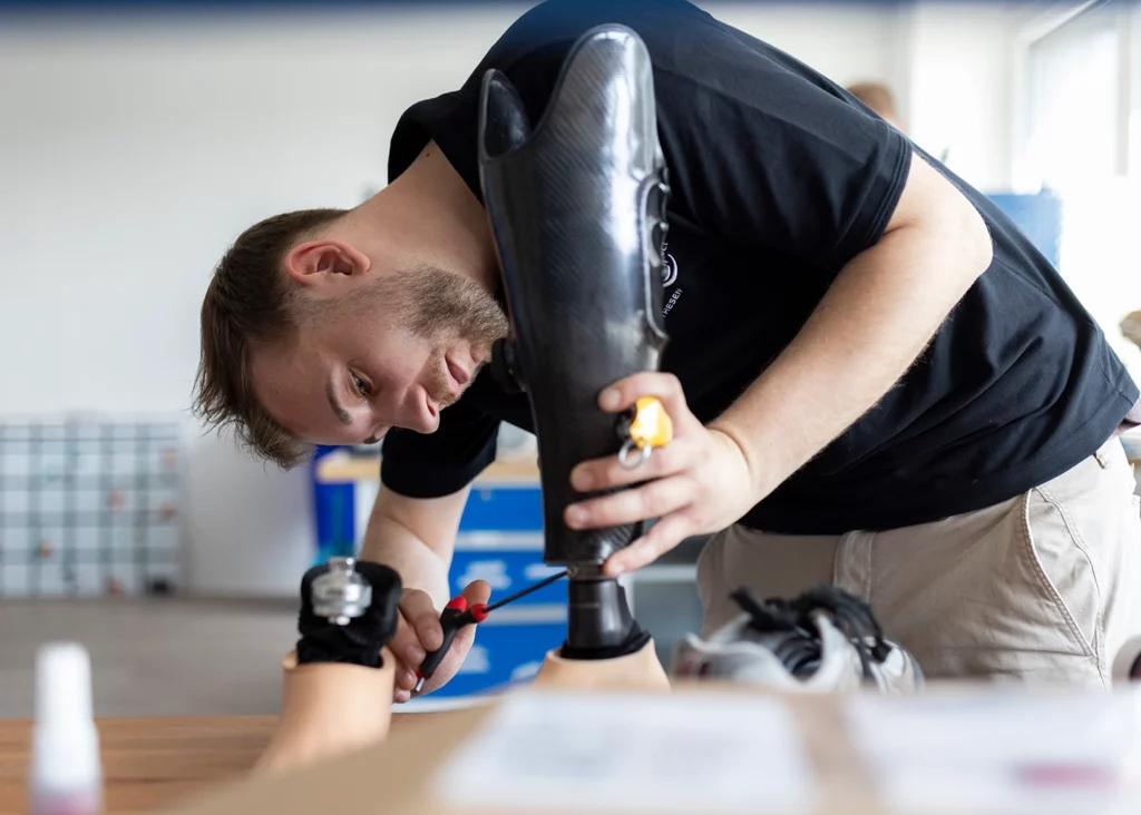Mitarbeiter von APT Prothesen schraubt an Beinprothese in der Werkstatt