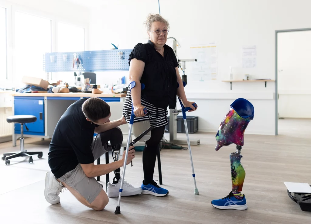 Orthopädietechniker versorgt Kundin mit Beinprothese in der Anprobe