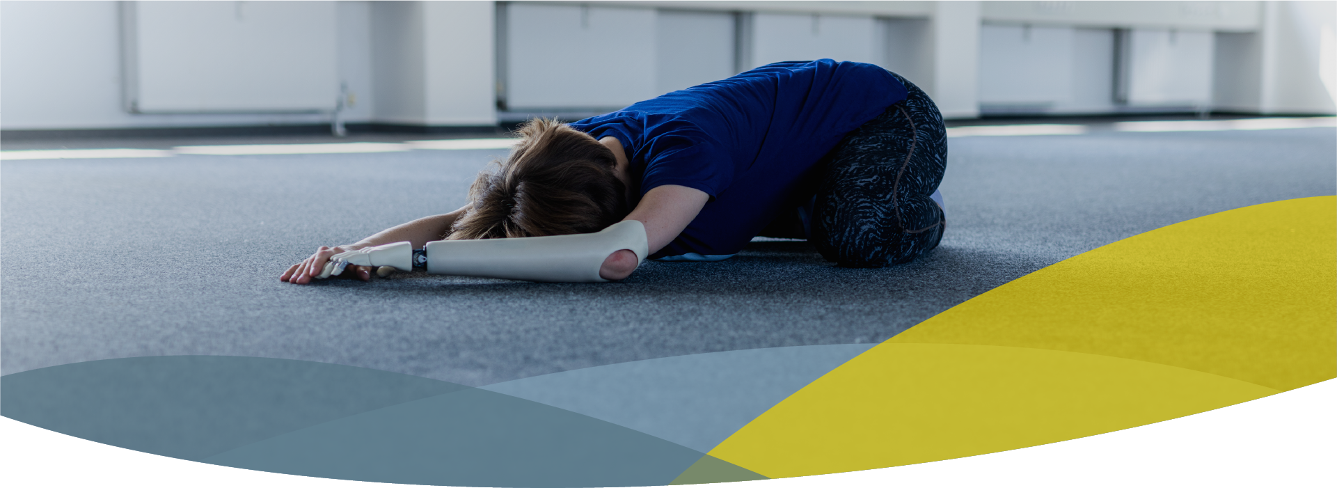 Headerbild für Rehabilitation, Frau macht Yogaübung auf dem Boden, Arme ausgestreckt nach vorne, trägt eine Armprothese