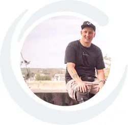 Kundenstimme von André, Kunde bei APT Bochum und Prothesenträger. Er sitzt auf einer Mauer und hat rechts seine Unterschenkelprothese.
