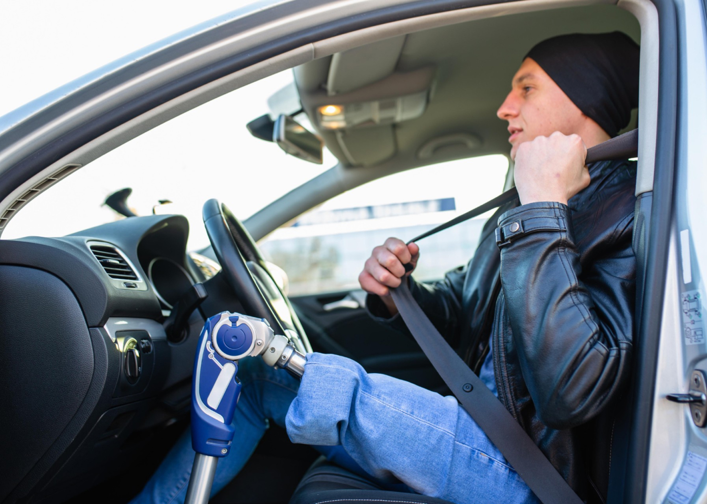 Mann mit Beinamputation sitzt im Auto und schnallt sich an