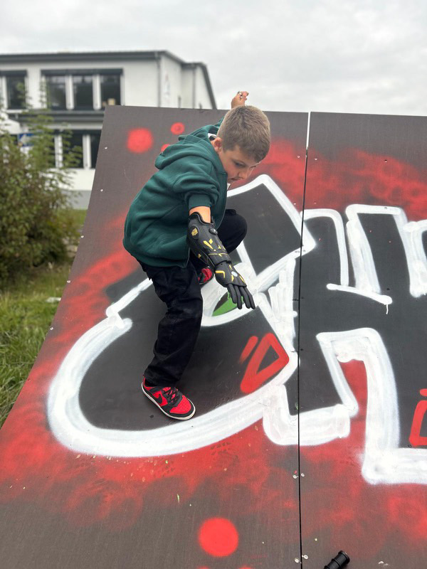 Kind trägt eine schwarz-gelbe Armprothese und steht auf einer Skaterrampe